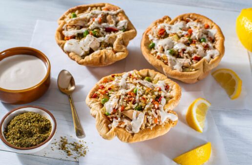 baked pita bowls stuffed with mediterranean style chicken rice peas carrots bell peppers and tahini sauce